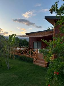 a house with a wooden deck next to a yard at Sera Pansiyon in Cıralı