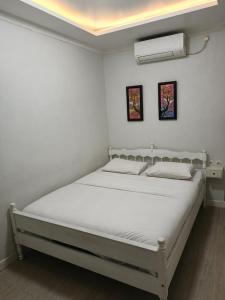 a white bed in a white room with two pictures on the wall at Homestay Harmonie Cepu in Padangan