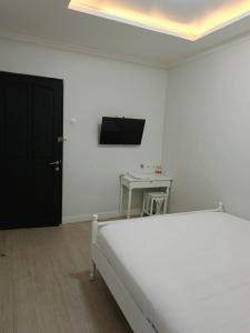 a white room with a bed and a tv on the wall at Homestay Harmonie Cepu in Padangan