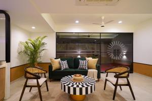 a living room with a green couch and two chairs at Olive Hotel Wakad by Embassy Group in Pune