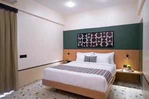 a bedroom with a large bed and a green wall at Olive Hotel Wakad by Embassy Group in Pune +18 photos