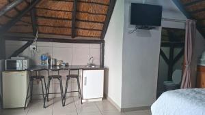 a kitchen with a counter and stools in a room at Oppihoek Gastehuis in Kroonstad +19 photos
