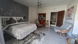 a bedroom with a bed and two chairs in it at Oppihoek Gastehuis in Kroonstad