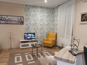 a living room with a tv and a yellow chair at Edina Apartman in Sátoraljaújhely