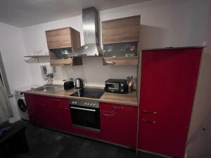 a small kitchen with red cabinets and a sink at Kenny's place in Essen +17 photos