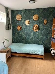 a bedroom with a bed with straw hats on the wall at huize Louwra in Egmond-Binnen
