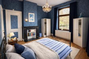a blue bedroom with a bed and a chandelier at Maison de Maître in Liège