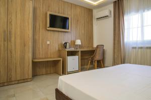 una camera da letto con un letto, una scrivania e una TV di Hotel Opera a Rouiba Altre 24 foto