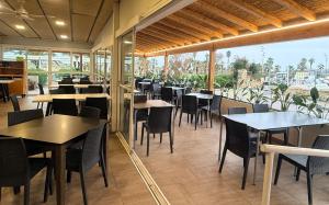 a restaurant with tables and chairs and a large window at Pensión La Ola in Grao de Castellón
