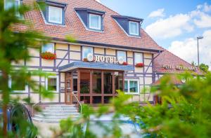 - un bâtiment avec une terrasse couverte et des escaliers devant dans l'établissement Hotel & Restaurant Ernst, à Giesen