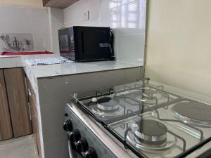 a stove top in a kitchen with a microwave at Gracious homes in Narok