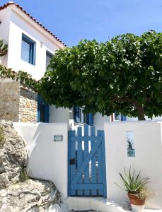 a blue door on a white house with a tree at Oikies Skiathos in Skiathos