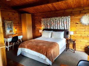 a bedroom with a bed and a desk in a log cabin at Tegwaan's Nest B&B in Mooiriver
