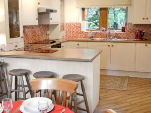 a kitchen with white cabinets and a counter with bar stools at Fell View in Kettlewell
