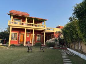 a red house with two benches in front of it at Peepal in Aranyaa Cottage Homestay Vrindavan in Vrindāvan