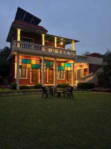 a large house with benches in front of it at Peepal in Aranyaa Cottage Homestay Vrindavan in Vrindāvan
