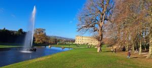 a fountain in a park next to a lake with a building at The Dog & Partridge Country Inn in Ashbourne