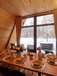 a wooden table in a room with a large window at Cabana Vatra Râului in Lazuri