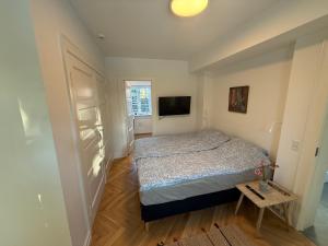 a small bedroom with a bed and a television at Ny & hyggelig moderne suite in Hvidovre