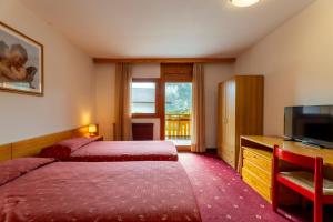 a hotel room with two beds and a flat screen tv at Beohotel in San Lorenzo in Banale