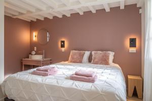 a bedroom with a large white bed with pink towels on it at Boonackere Cottage in Oosterzele