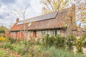 an old brick house with solar panels on the roof at Boonackere Cottage in Oosterzele