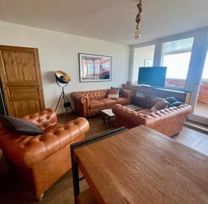 a living room with leather couches and a television at COAST HOUSE Havenquartier in Bremerhaven