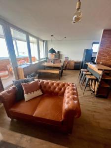 a living room with a brown leather couch and tables at COAST HOUSE Havenquartier in Bremerhaven