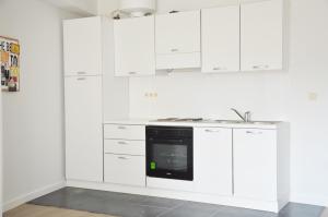 a white kitchen with white cabinets and a black oven at Flat Sympa next Grand Place in Brussels