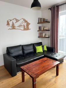 a black leather couch in a living room with a coffee table at TatryForRest in Starý Smokovec