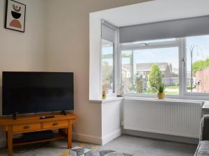 a living room with a flat screen tv and a window at Carolyn House in Ellington