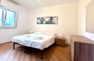 a white bedroom with a bed and a window at JuliaHome in Marina Julia