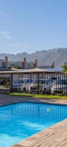 a swimming pool in front of a building with cars at V's Condo in Gordonʼs Bay