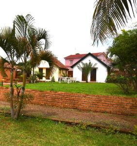 a house with a brick wall and a palm tree at SNI-Village Ambohidratrimo au bord du Lac Andranotapahana in Ambohidratrimo