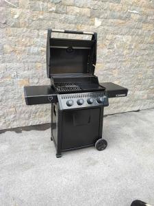 a black barbecue grill sitting next to a brick wall at APARTMAJI SILVA in Slap ob Idrijci