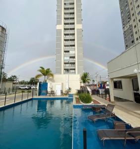 a pool with chairs and a rainbow in the background at Paraiso Ponta de Campina in Cabedelo