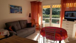 a living room with a couch and a sliding glass door at O'Paloma - appartement T2 au port - Parking - Terrasse in Saint-Cyprien-Plage