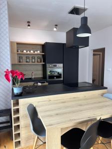 a kitchen with a wooden table and black cabinets at TatryForRest in Starý Smokovec