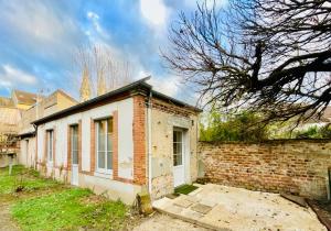 an old brick building in a yard with a tree at Les Jardins Bas in Moulins