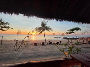 a beach with a palm tree and the sunset at Relax Bay Beach Resort in Ko Lanta