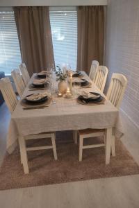 a dining room table with white chairs and a gray table cloth at Tilava uudistettu perheasunto in Rovaniemi