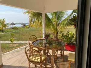 a glass table and chairs on a patio with a view of the ocean at Residence Coco Plage in Elinkinde