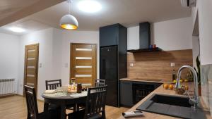 a kitchen with a table and a kitchen with black cabinets at Dom pośrodku Roztocza in Oseredek
