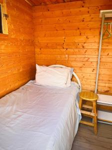 a bed in a wooden room with a wooden wall at Blue Moon Cabin in Willemstad
