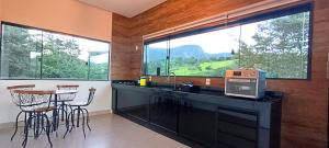 a kitchen with a counter with a table and some windows at Chalé Vertente da Canastra in São Roque de Minas