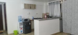 a kitchen with a counter with a microwave and a refrigerator at Modern 1BR Apartment in Membley & near Ruiru Bypass, Kenyatta University & AMREF, Fast WiFi & Parking-Ruiru Membley in Ruiru