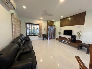 a living room with a leather couch and a tv at Aarna Villa nr Valvan Dam in Lonavala