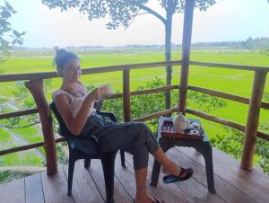 a woman sitting in a chair drinking a cup of coffee at lake paradise cabana in Tissamaharama