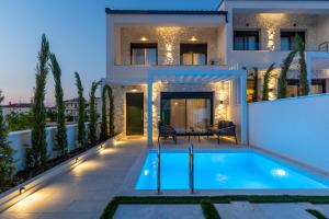 a villa with a swimming pool at night at Bela Villas in Kallithea Halkidikis