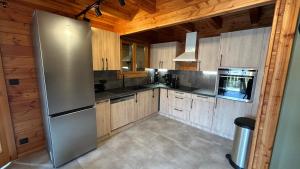 a kitchen with a stainless steel refrigerator and wooden cabinets at Chalet Tramontane, gîte tout confort in Xonrupt-Longemer